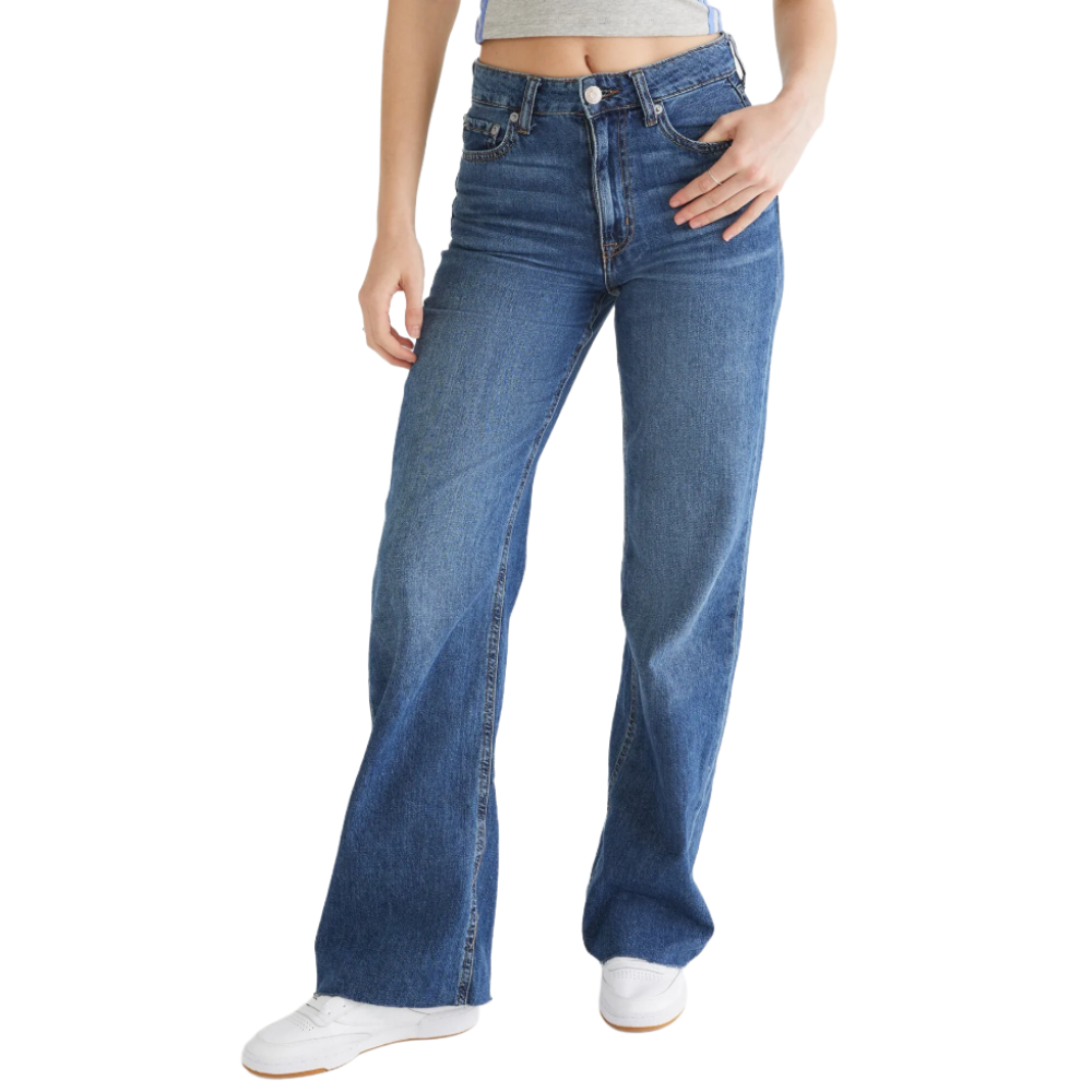A person is wearing high-waisted blue flared jeans and white sneakers.