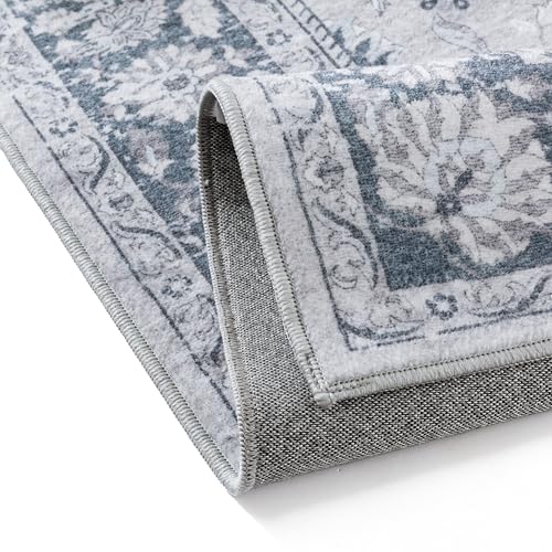 A corner of a decorative area rug with a blue and gray floral pattern is shown, highlighting its edge and woven backing.