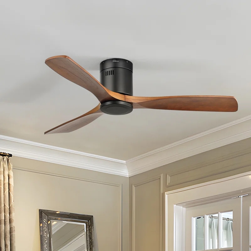 The Nicola 3-Blade Ceiling Fan features wooden blades with a sleek, modern design, attached to a compact, cylindrical black motor housing. It's mounted on a flat ceiling, offering a minimalist aesthetic.