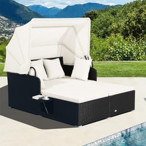 Outdoor daybed with a retractable canopy, featuring black wicker construction and white cushions, set near a pool with a scenic mountain backdrop.