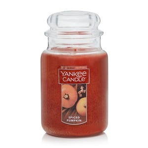 A large spiced pumpkin scented candle by Yankee Candle, displayed in a transparent jar with a label showing a pumpkin and spices.
