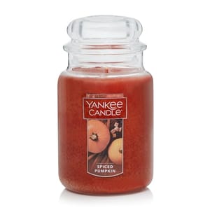 A large spiced pumpkin scented candle by Yankee Candle, displayed in a transparent jar with a label showing a pumpkin and spices.
