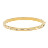 A gold-tone bangle bracelet featuring a row of small clear stones along the outer edge with an engraved \“kate spade NEW YORK\“ logo on the inner surface.