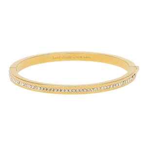 A gold-tone bangle bracelet featuring a row of small clear stones along the outer edge with an engraved \“kate spade NEW YORK\“ logo on the inner surface.