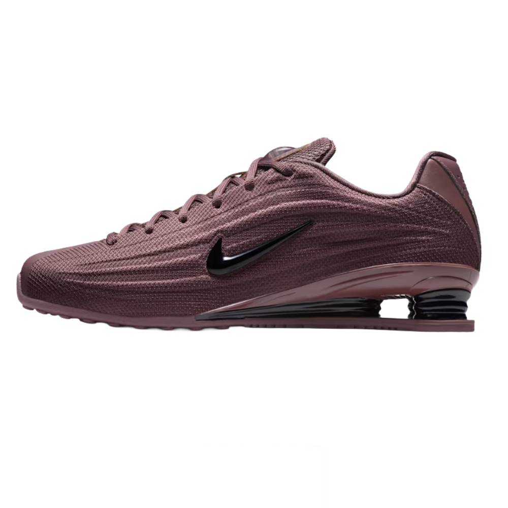 Nike Shox sneakers in a maroon color with a ribbed design, featuring a black swoosh and distinctive Shox cushioning in the heel.