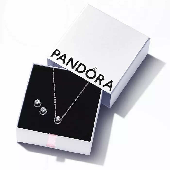 A Pandora jewelry set featuring a necklace with a circular pendant and matching stud earrings, displayed in an open white box.