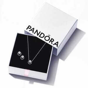 A Pandora jewelry set featuring a necklace with a circular pendant and matching stud earrings, displayed in an open white box.