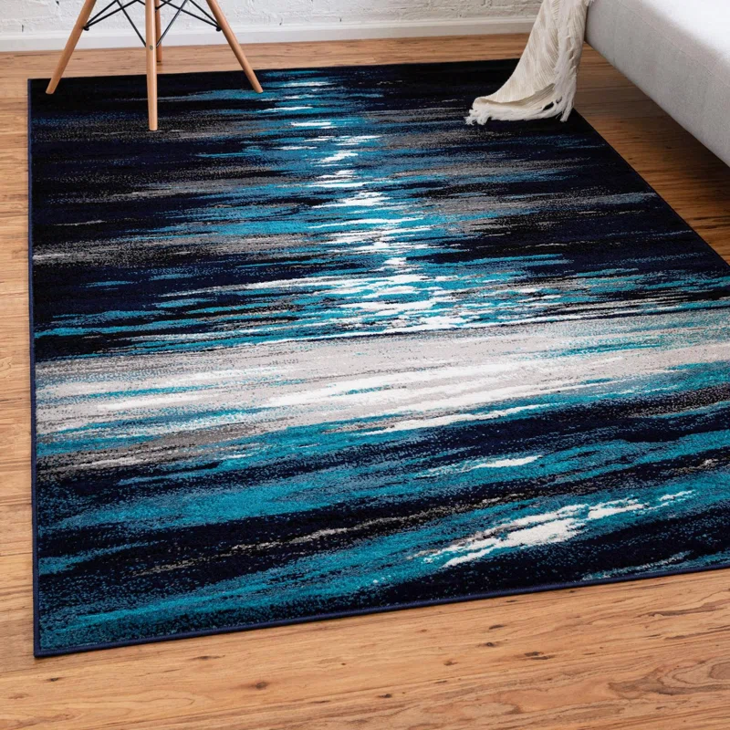 A rectangular area rug with blue and white abstract stripes on a wooden floor beside a chair and a sofa.