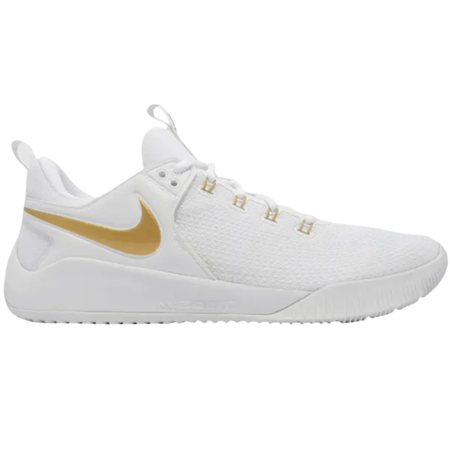 A white athletic shoe with a gold Nike swoosh logo, featuring a textured upper and cushioned sole.