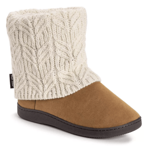 A brown slipper boot with a soft knit cream collar and black sole, featuring a cable knit pattern and a side tag.