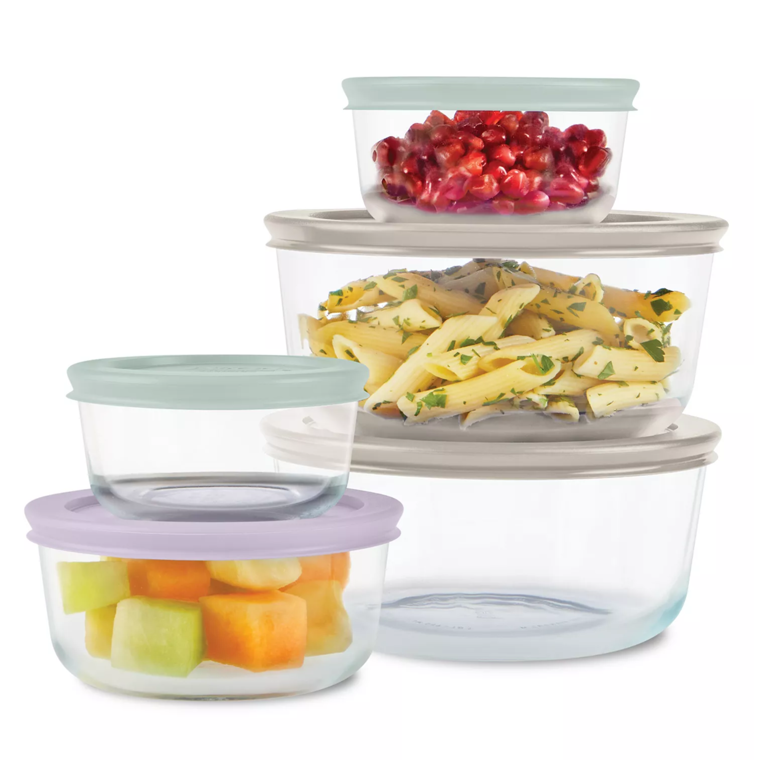 A set of clear glass food storage containers with pastel-colored lids, each filled with different foods like pasta, pomegranate seeds, and fruit cubes.