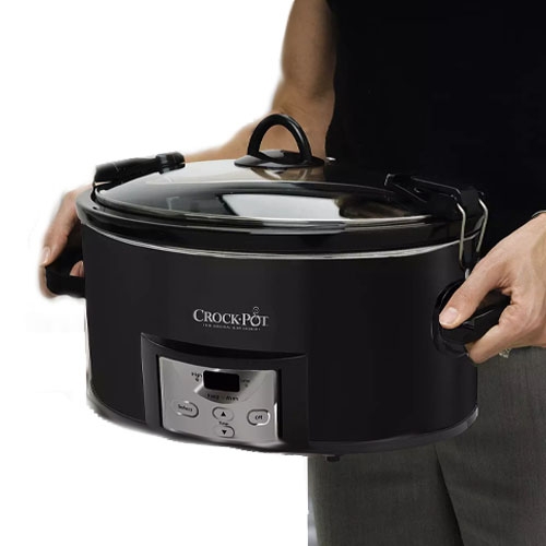 A person is holding a black Crock-Pot slow cooker with a digital control panel and a glass lid secured with metal latches.