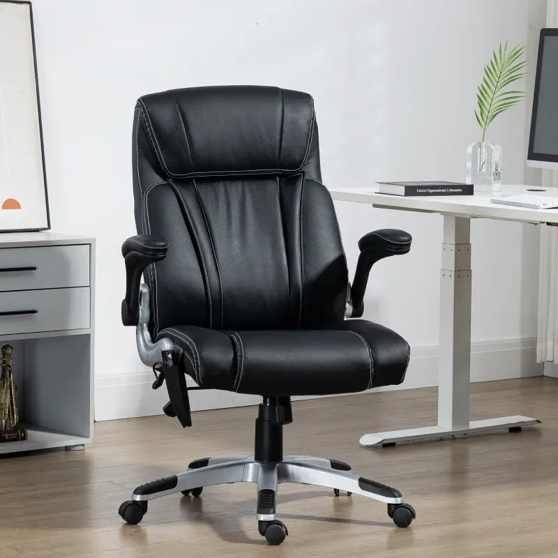 A black leather office chair with adjustable armrests and a chrome base is placed on hardwood flooring, next to a white desk with a computer and books.
