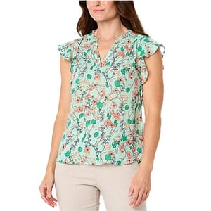 A woman wears a light green floral blouse with a V-neck and ruffled cap sleeves, paired with beige pants.