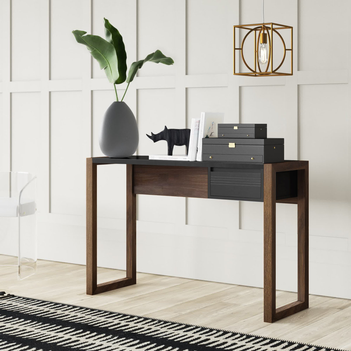 A modern console table features open rectangular wooden legs, sleek black surfaces, decorative boxes, a plant in a teardrop vase, and a small rhino sculpture under a geometric pendant light.