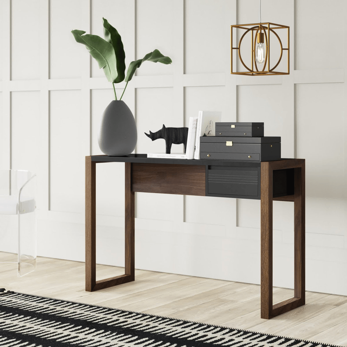 A modern console table features open rectangular wooden legs, sleek black surfaces, decorative boxes, a plant in a teardrop vase, and a small rhino sculpture under a geometric pendant light.