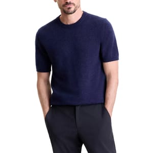 A man is wearing a short-sleeved navy knit sweater paired with dark pants.