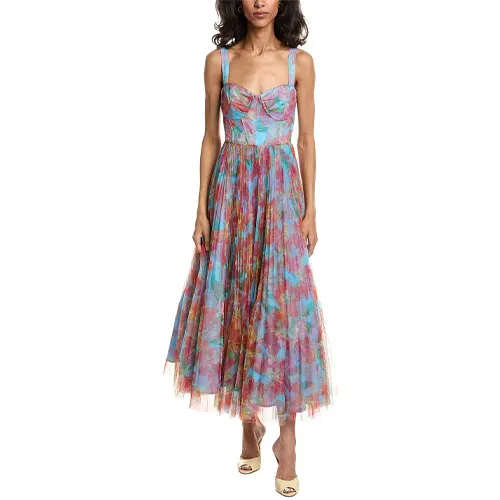 A woman is wearing a colorful floral-print midi dress with a fitted bodice, pleated skirt, and wide shoulder straps, paired with open-toe heels.