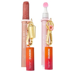 Two Tarte x Dunkin' collaborative items: a Maracuja Juicy Lip balm and a Maracuja Juicy Lip Plump. Each features a keychain charm, one shaped like a coffee cup and the other like a donut.