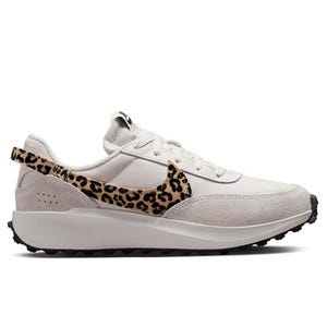 White sneaker with suede accents and a leopard print swoosh, featuring a thick sole and structured design.