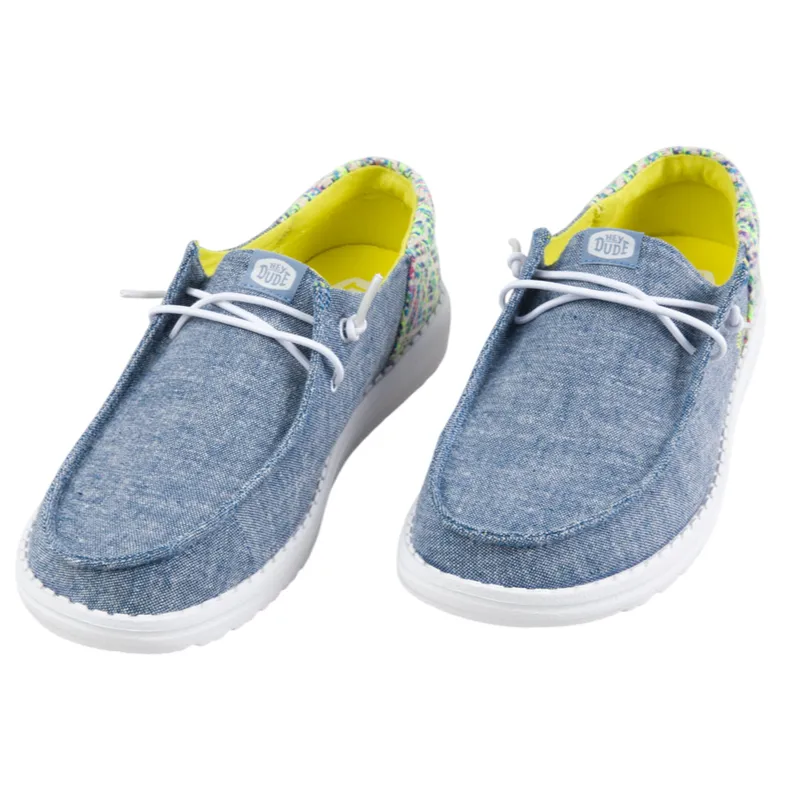 Casual slip-on shoes with light blue denim fabric, white laces, and a multicolored heel accent. Bright yellow interior.