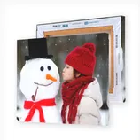 A canvas print features a child in a red hat and scarf interacting with a snowman wearing a black top hat and red scarf, set in a snowy backdrop.