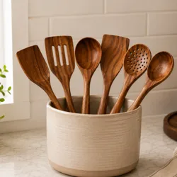 A set of wooden kitchen utensils, including spatulas and spoons, is displayed in a beige ceramic holder on a countertop.