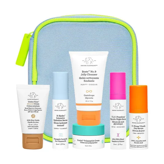 Skincare set featuring Drunk Elephant's Beste No. 9 Jelly Cleanser, B-Hydra Intensive Hydration Serum, T.L.C. Framboos Glycolic Night Serum, C-Firma Fresh Day Serum, Protini Polypeptide Cream, and Umbra Tinte Mineral Cream, all in travel sizes.