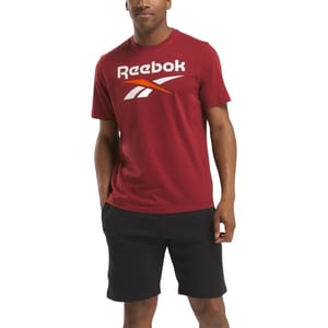 A person wears a red Reebok T-shirt with a logo and black shorts.