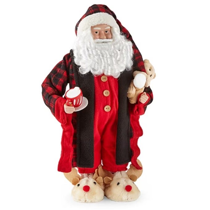 An 18-inch Santa figurine dressed in plaid pajamas, a red robe, and reindeer slippers, holding a teddy bear and a mug with a plate, featuring a white curly beard.
