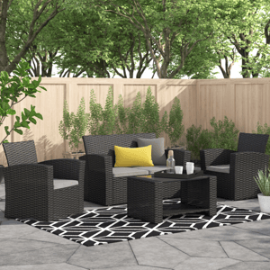 A 4-piece patio set featuring a sleek black rattan finish, including two armchairs, a loveseat with gray cushions, and a coffee table, all arranged on a geometric-patterned rug, with yellow and gray accent pillows enhancing the modern outdoor setting.