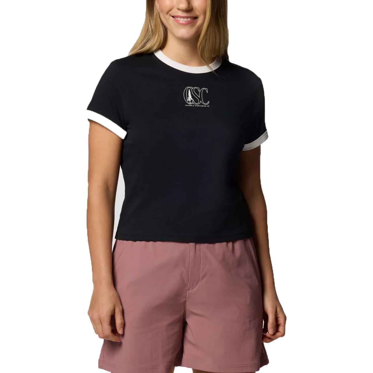 A person is wearing a black and white ringer t-shirt with \“OSC\“ printed on it and mauve shorts.