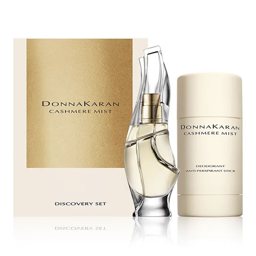 The 2-piece Donna Karan Cashmere Mist Gift Set includes a perfume bottle with an elegant, sculptural design and a deodorant antiperspirant stick, both in soft gold and beige packaging.