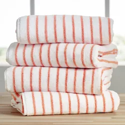Stack of four white towels with orange stripes on a wooden surface, against a blurred window background.