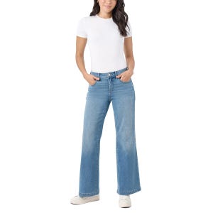 A woman is wearing a white short-sleeve top, light blue wide-leg jeans, and white sneakers.