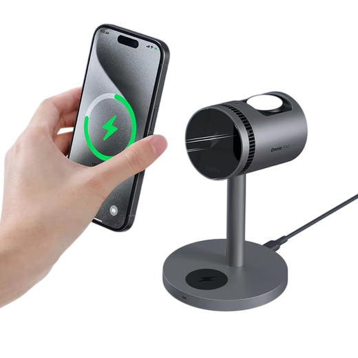 A hand is placing a smartphone onto a wireless charging stand, which also appears to have a mini projector mounted on it.