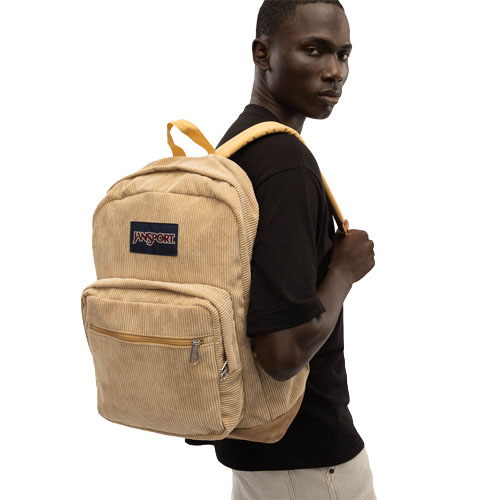 A person carries a beige Jansport backpack with a corduroy texture, featuring a front zipper pocket.