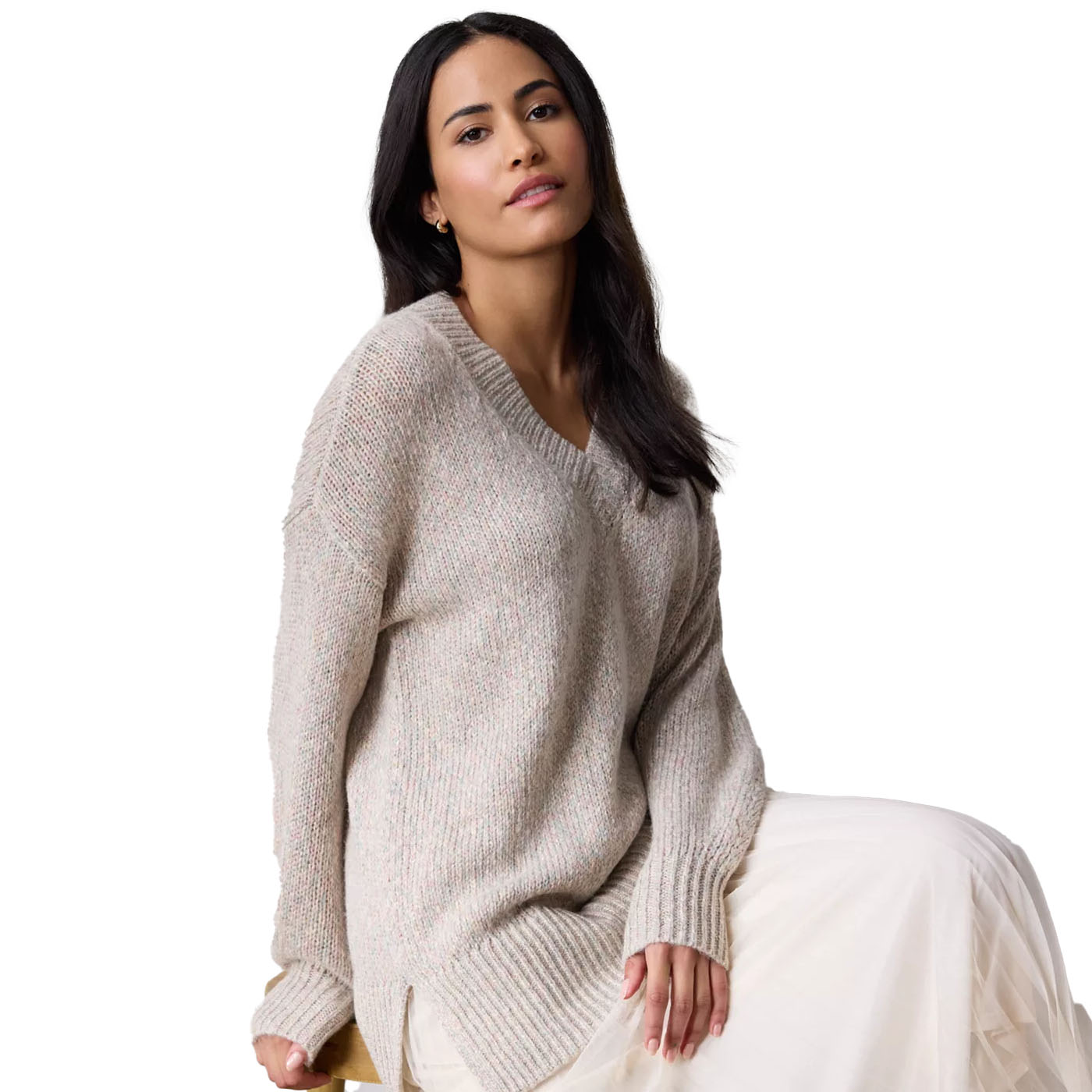 A woman is modeling a beige Lauren Conrad tunic sweater with a V-neck and relaxed fit, paired with a light flowing skirt. The sweater features ribbed detailing on the cuffs and hem for subtle texture.
