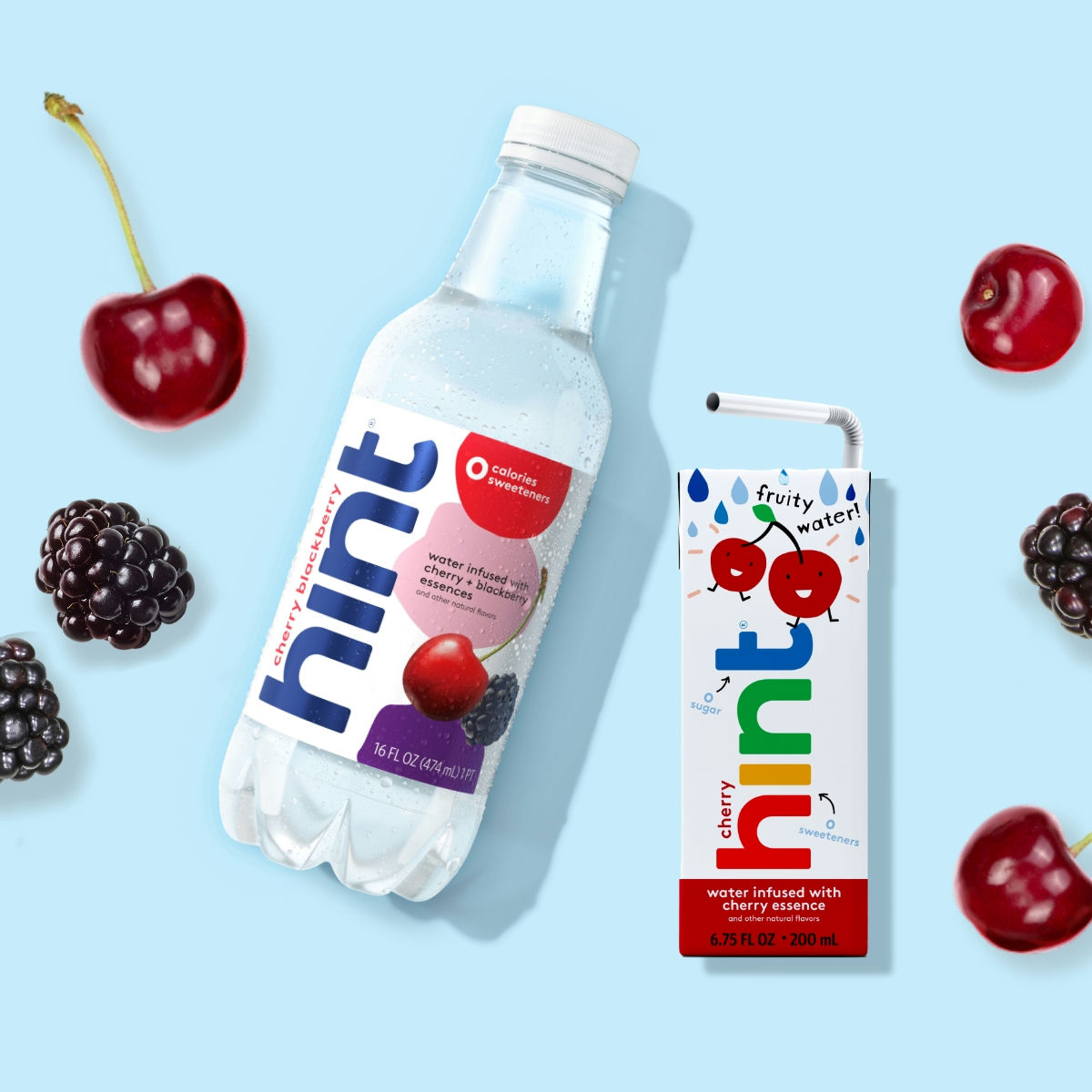 Two Hint flavored water products, one in a clear plastic bottle and one in a small juice box, accompanied by fresh cherries and blackberries.
