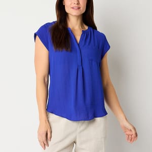 Woman wearing a blue short-sleeved blouse with a mandarin collar and a front pleat detail. She's also wearing beige trousers.