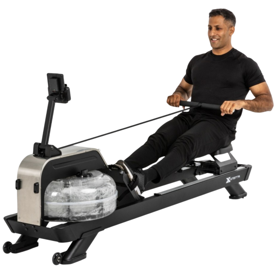 A person is using a water rower machine with a transparent resistance tank and a digital display. The rower is branded \“Xterra.\“