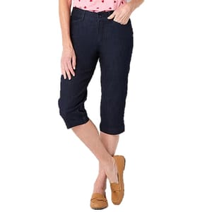 Dark denim capri pants with a slim fit, reaching just below the knees, paired with tan moccasin-style loafers and a pink top with a red heart pattern.