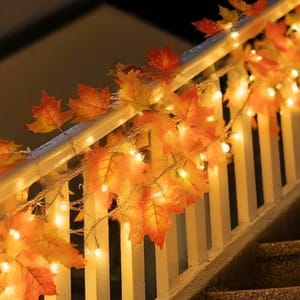 String lights with autumn leaves decor are wrapped around a stair railing.