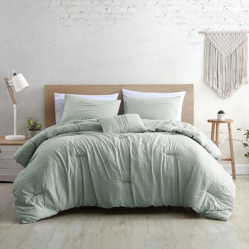A mint green duvet cover set with pillowcases on a bed, complemented by a white bedside lamp and a woven wall hanging.