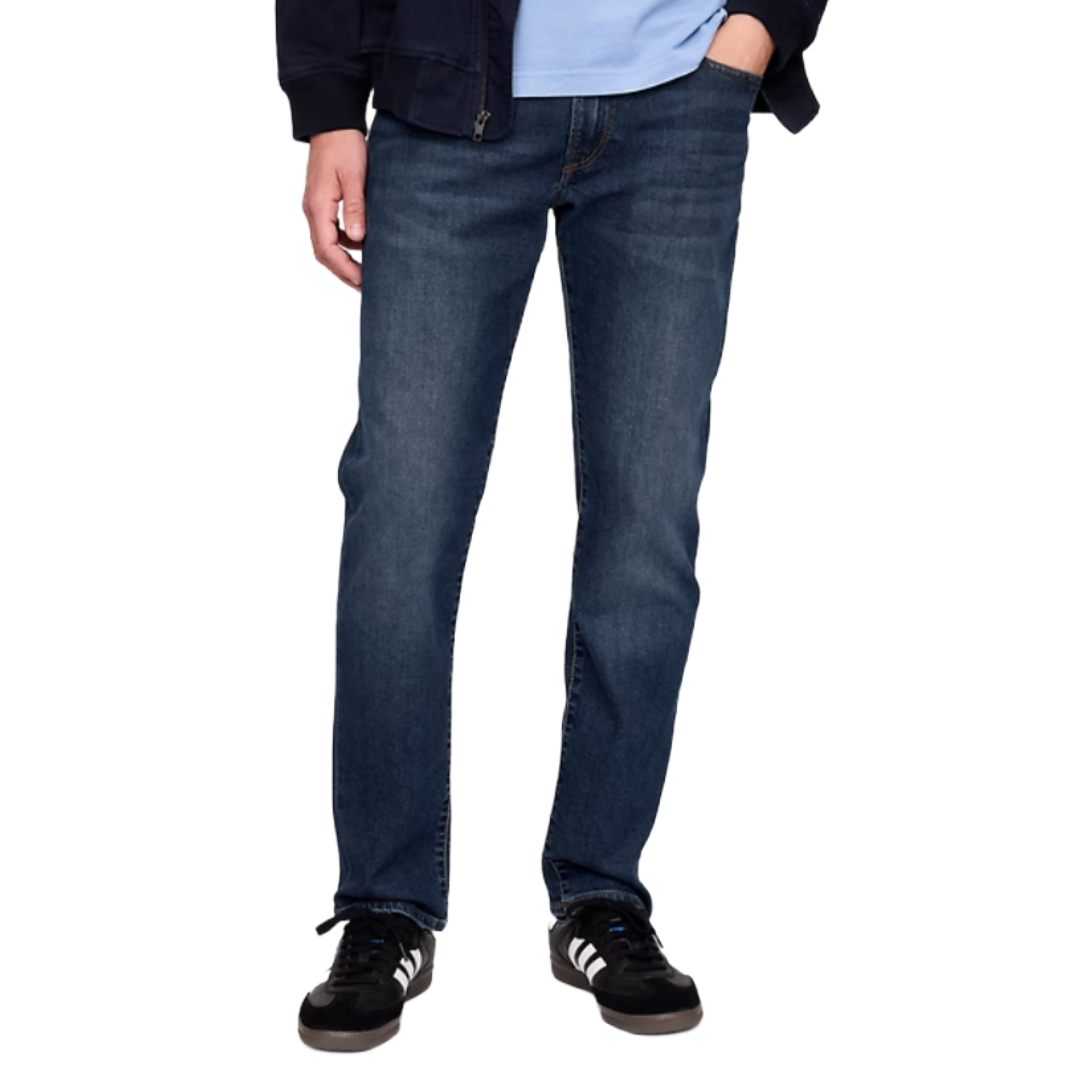 A person is wearing dark blue straight-leg jeans, black Adidas sneakers with white stripes, and a navy jacket over a light blue shirt.