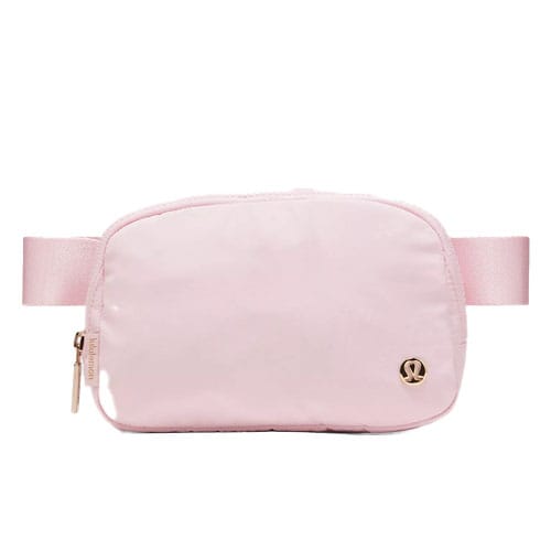 A light pink crossbody bag with a zipper and an adjustable strap, featuring a small logo emblem on the front.