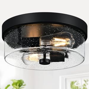 Flush mount ceiling light with a black base and seeded glass shade, featuring two vintage-style exposed bulbs.