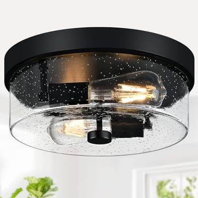 Flush mount ceiling light with a black base and seeded glass shade, featuring two vintage-style exposed bulbs.