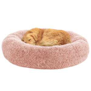 A golden retriever is curled up on a round, fluffy pink pet bed with a soft texture.
