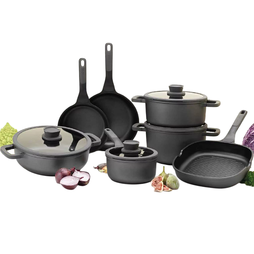A cookware set including various pots, pans, and a grill pan in a sleek black finish, each with ergonomic handles, some featuring glass lids. Surrounded by fresh vegetables for context.